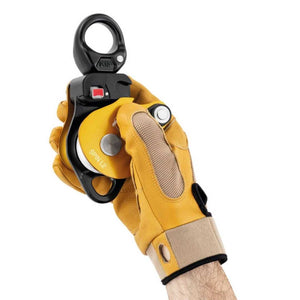 Yellow Petzl Spin L2 a demonstration of its operation with a white bull rope. An arborist's hand with the Petzl glove pulls the rope